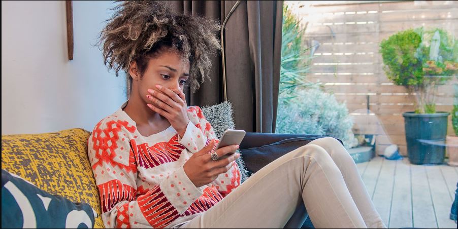 une femme choquée devant son smartphone